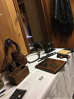 Vintage leather stirrups, cast iron ice tongs, onyx wood elephant bookends, horse wall art, pig hot plate, carved eagle plaque, small wood box on white surface