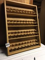 Front angled view of the wooden PEZ display case showing all five shelves with slots for dispensers.