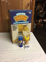 Photo of the Wear-Ever Popcorn Pumper box with the popcorn popper and two shakers in front on a white table surface.
