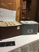 Brown and gray quilted storage cases side by side on a table. Cases have multiple compartments inside for storing stemware glasses.
