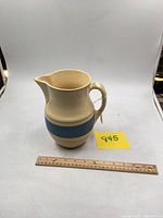 Blue and cream Roseville pitcher with handle and spout shown with a ruler for scale.