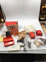 Display of plastic train houses, platforms, stairs, and various small accessories laid out on a white background.