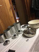 Full set of vintage aluminum canisters, Kitchen Craft bowls, and Bayal spice box displayed on table
