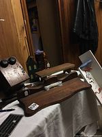 Photo of vintage wooden telephone box, two wooden wall shelves, wooden spoons, wooden candleholder, part of a cuckoo clock, and house-shaped wooden basket arranged on a surface