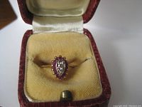Ring displayed in red leatherette box with yellow velvet interior