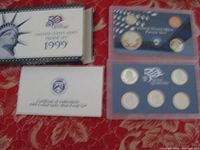 Full overview of the lot showing the 1999 United States Mint Proof Set box, certificate, and two sealed plastic cases containing coins including state quarters.