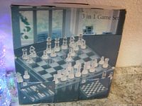 Front and side views of the box showing a 3 in 1 game set featuring a glass chess game with clear and frosted glass pieces and a glass checkered board.