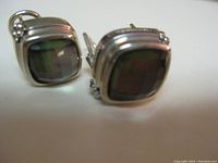 Pair of square-shaped earrings showing large faceted dark-colored stones set in sterling silver, positioned to display the stone and silver setting.