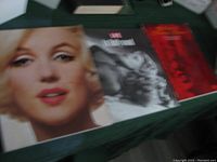 Three vintage books laid out on a table, with two Marilyn Monroe themed large books and one red book about Hollywood.