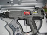 Close-up of Senco DuraSpin electric nail gun inside its gray plastic carrying case, showing label and design details.