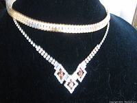 Napier crystal rhinestone necklace with gold-tone herringbone chain displayed together on black jewelry bust.