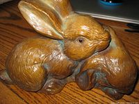 Close-up image showing detailed fur texture and glass eyes of one rabbit in the stone sculpture of two rabbits resting together.