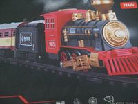 Close-up photo of the detailed black and red locomotive with gold accents and attached coal and passenger cars on black plastic tracks.