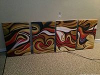 Four abstract acrylic paintings on canvas, displayed in a row on a carpeted floor leaning against a baseboard wall.