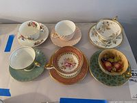 Overhead view of all six teacup and saucer sets showing variety of patterns