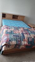 Full view of wooden bed frame with headboard storage, mattress and quilt in place