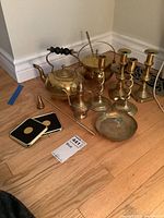 Photo showing full lot with brass candle sticks, teapots, coasters, bowl, metal candle snuffer, stone heater, and rod.