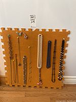 Photo shows full set of twelve necklaces and two brooches on orange foam background