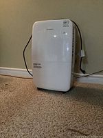 Full front view of white Garrison dehumidifier plugged in with power cord visible.