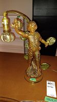Full view of the metal figural lamp showing the boy holding a bird and leaf, standing on a round base.