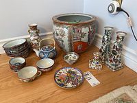 Full view of all ceramic items described: pot, candlesticks, teapot, bowls, teacups, and vase grouped on floor.