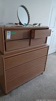 Front and side view of the high boy dresser showing seven drawers, some drawer open, with various items on top not included in sale.