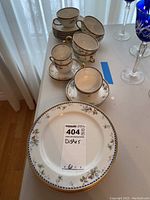 Photo showing the variety of cups and luncheon plates arranged on table, highlighting floral and gold rim details.