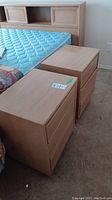 Pair of wooden night stands placed near a bed, arranged side by side on carpet. Shows top, front and some side views.