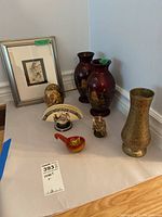 Photo showing entire lot of vases, framed print, and small decorative items on white surface near wall corner.