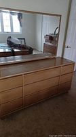 Front view of vintage wooden dresser with large rectangular mirror mounted on top. Dresser has multiple drawers.