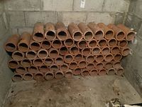 Wide angle view of stacked terracotta tubes in basement storage area, showing total quantity and usage context