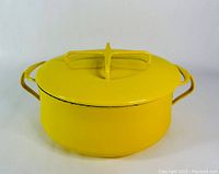 Yellow enamelware pot with lid, showing cross-shaped handle and integrated side handles, displaying overall condition and color.