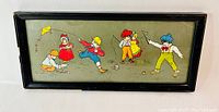 Framed illustration showing children in Victorian clothes playing various games including kite flying, ball playing, and fishing.