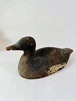 Side angled view showing the carved shape and worn painted surface of the duck decoy.