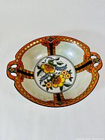 Top-down view of Noritake bowl showing Art Deco pattern on rim and handles, with floral design in center.