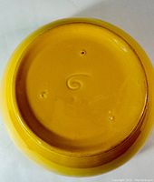 Photo of the bottom of the yellow ceramic mixing bowl showing embossed number 6 or 9 on the base.
