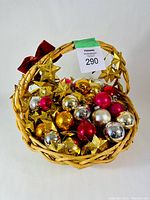 Woven basket filled with assorted vintage glass Christmas ball ornaments in multiple colors with gold star garland wrapped on the handle