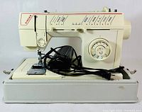 Front view of Singer Melodie 5808C sewing machine with foot pedal and cords, placed in a plastic base.