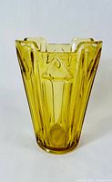 Front view of the amber glass vase showing detailed Art Deco geometric patterns and angular flared top edges.