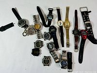 Overview photo of 14 watches on white background, mix of digital, analog and pocket styles.