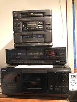 Stack of audio components including Sharp 3-disc CD player, Sharp tuner/amplifier, Sharp cassette deck, Pioneer cassette deck, Sony CD changer/player