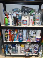 Full view of metal shelving unit with multiple shelves containing assorted cleaning and pest control products, various bottles and containers seen clearly.