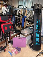 View of fitness equipment lot showing TorsoTrack board, Easy Gym bench with red cushions, Nano Gym case, dumbbells, and wrist weights.