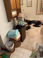 Photo of wicker hamper and smaller bin with stacks of towels on top in a room with beige carpet.