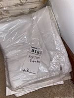 Folded king size sheets in plastic with a MaxSold tag