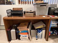 Overview of desk with various office storage boxes, paper, files, briefcases beneath it