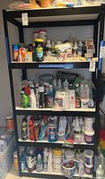 Two black metal shelving units shown with various household and cleaning items stored on shelves. Shelves appear sturdy and adjustably mounted on vertical supports with tools needed for disassembly.