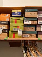 Photo showing shoe boxes from various brands including Bearpaw, Dr. Scholl's, BareTraps, and Clarks stacked in storage.