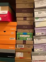 Stacked shoe boxes from various brands including many Clarks boxes labeled with sizes and styles.