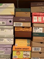 Stack of shoe boxes featuring brands Clarks, Earth Spirit, PureSole with hand notations for colors and sizes